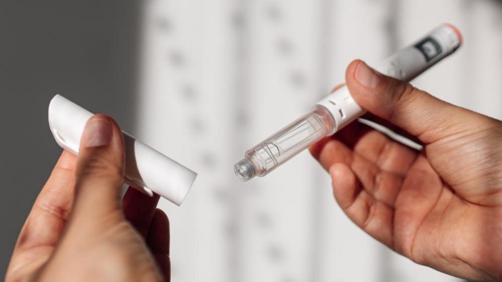 Woman holding a GLP‑1 weight‑loss injection pen